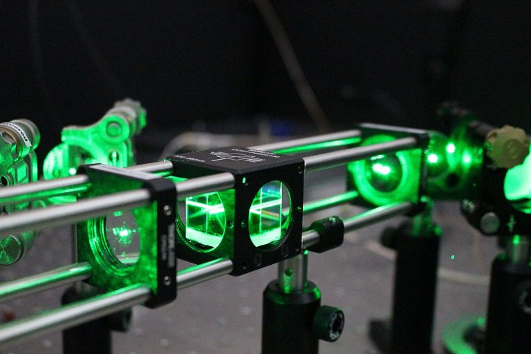 A green laser hitting a beamsplitter on an optical table in Gavin Morley's lab